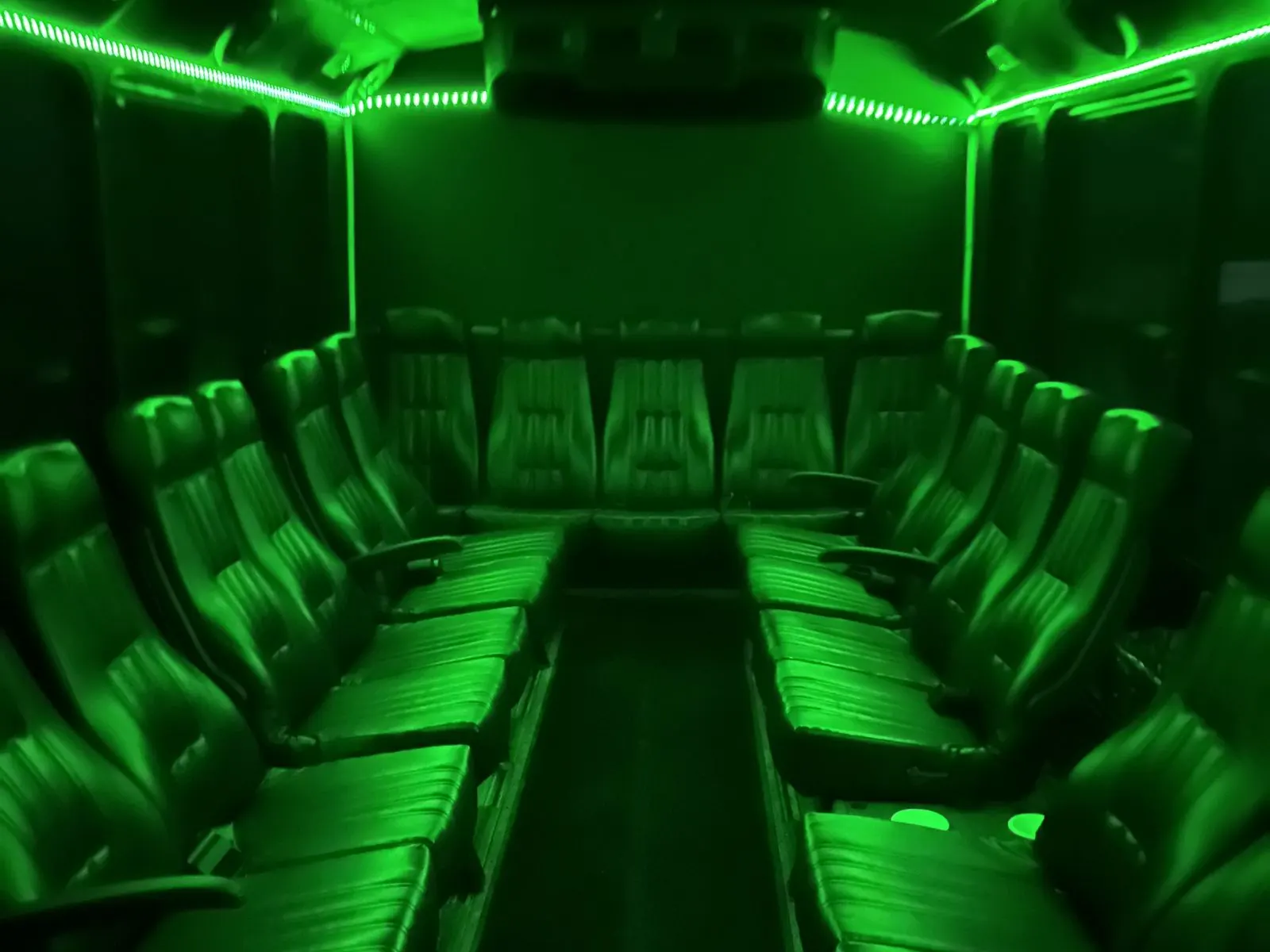 Inside the Black Tie Affair party bus: rows of leather seats under green LED lighting